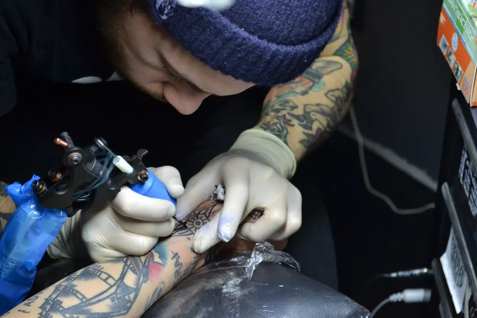 Tatuador profesional trabajando en el antebrazo de un cliente en un estudio