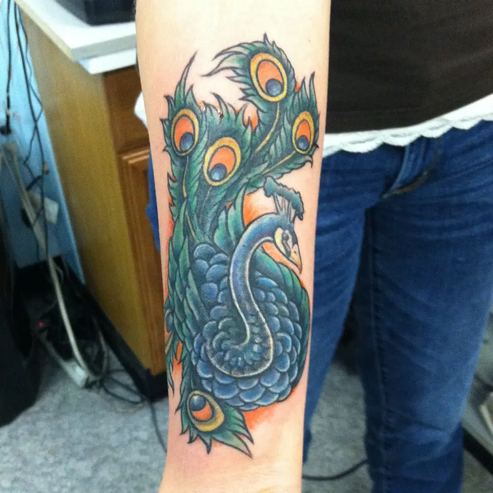 Tatuaje de un pavo real a color en el antebrazo