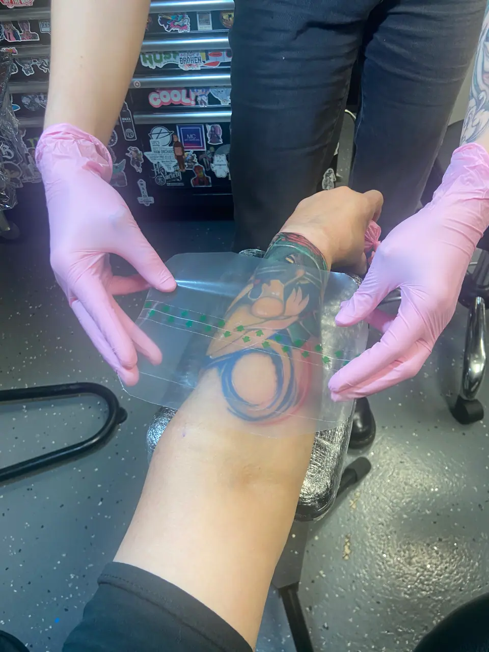 Tatuador aplicando un film protector transparente sobre un tatuaje recién hecho